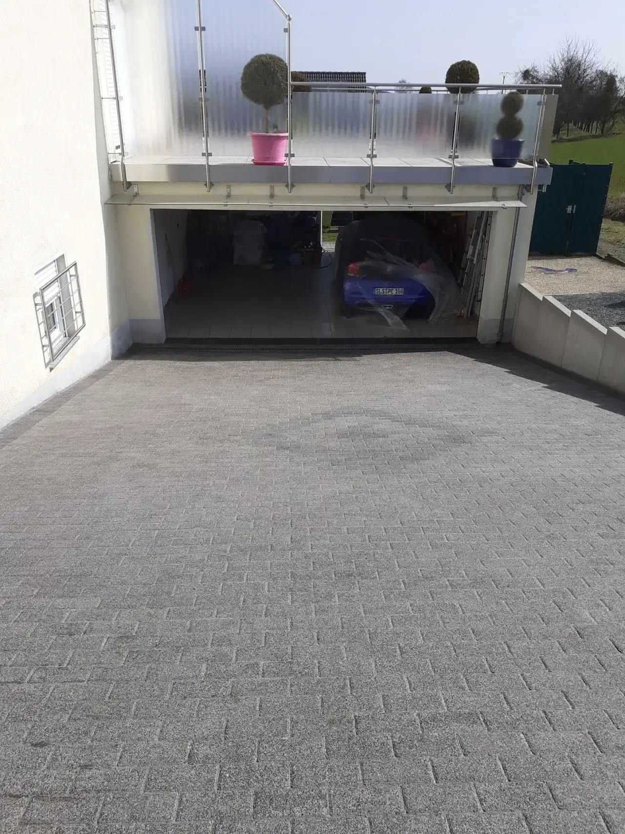 Zufahrt zu einer offenen Garage, der Belag ist gleichmäßig hell und trocken, im Garageninneren steht ein Auto