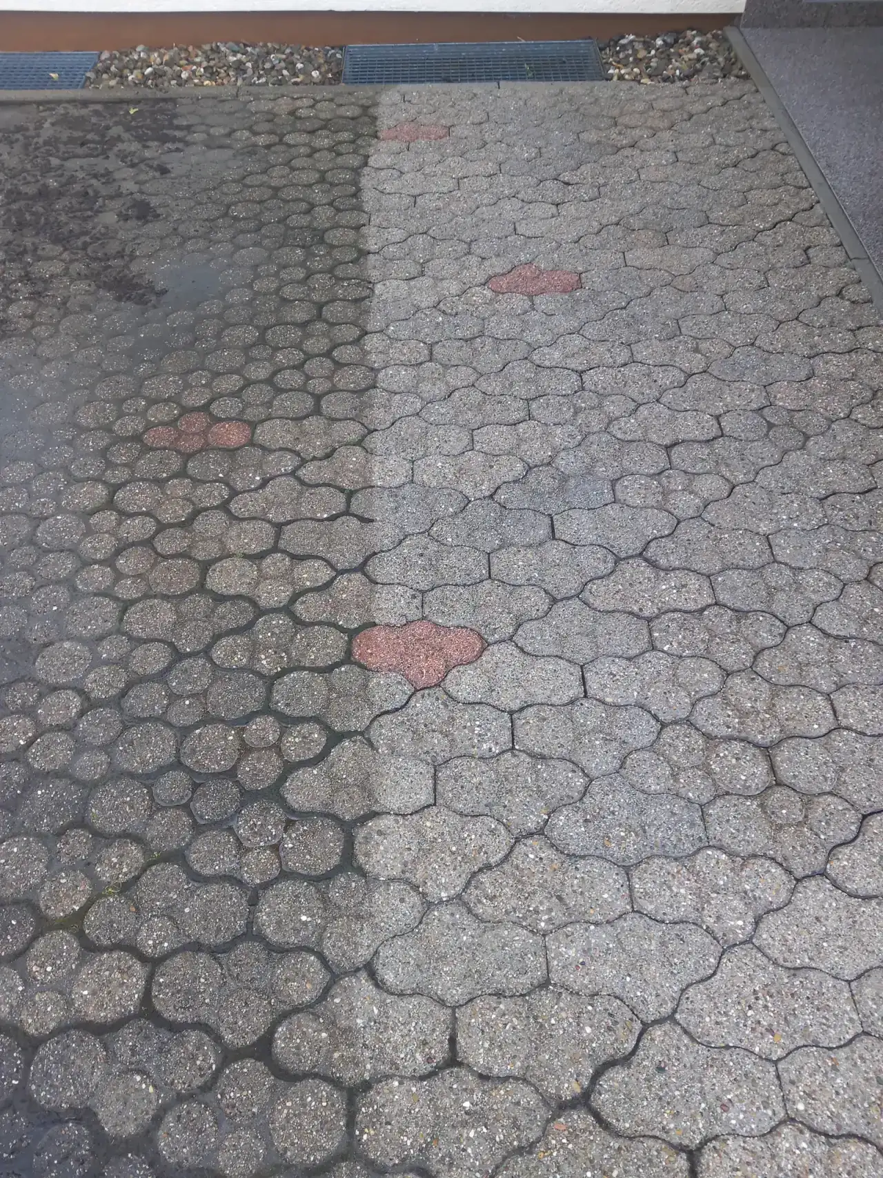 Verbundpflaster mit Knochensteinen und roten Akzentsteinen, durch die Fläche läuft ein hellerer Streifen, der sich klar vom übrigen Belag absetzt