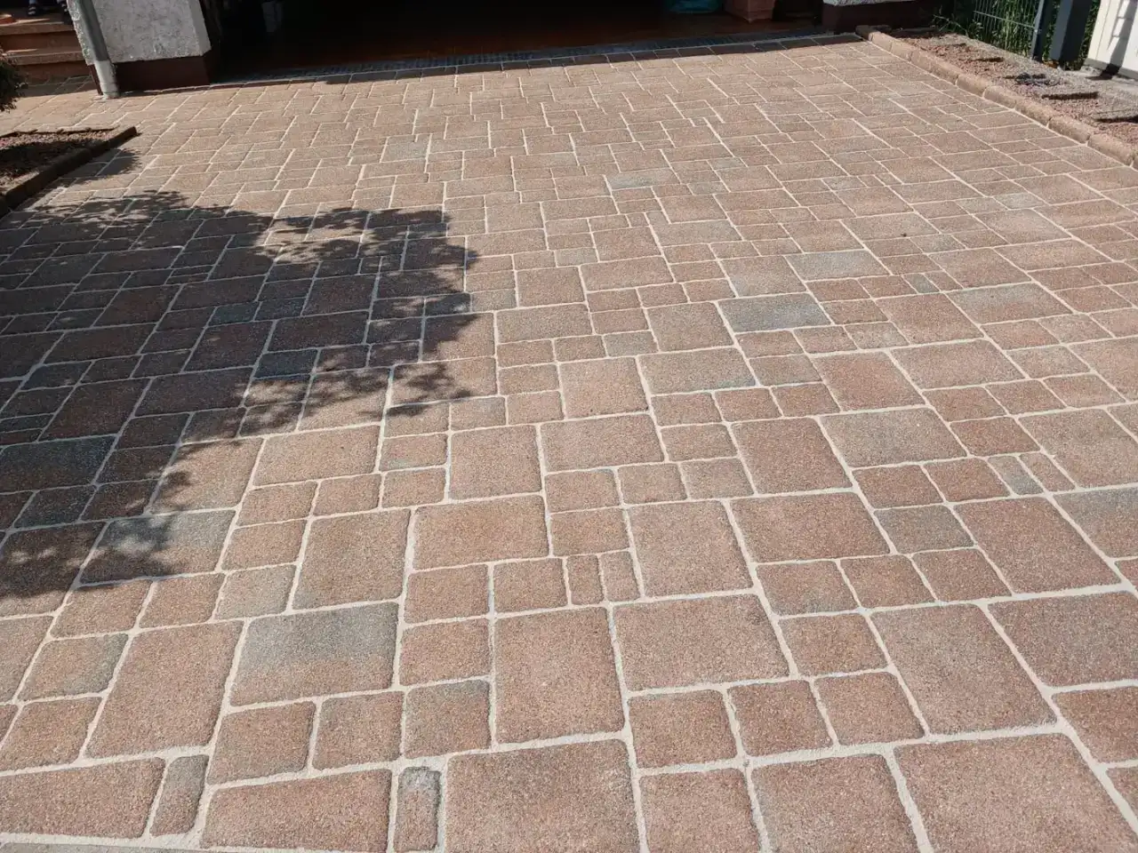 Gereinigte Hofeinfahrt aus Betonpflaster vor einer Garage und dem Hauseingang