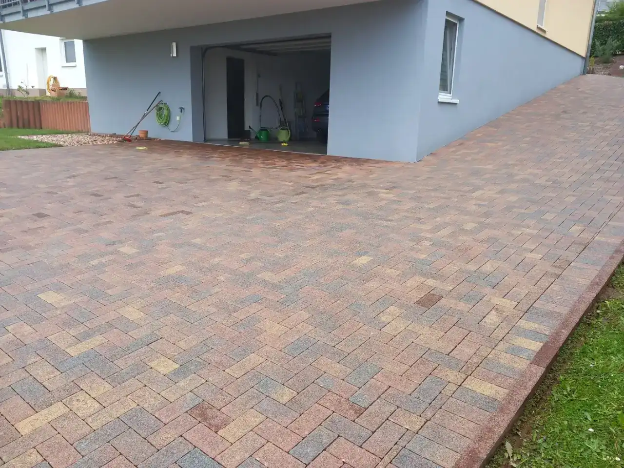 Gereinigte Einfahrt vor einer Garage, Betonpflaster im Fischgrätverband