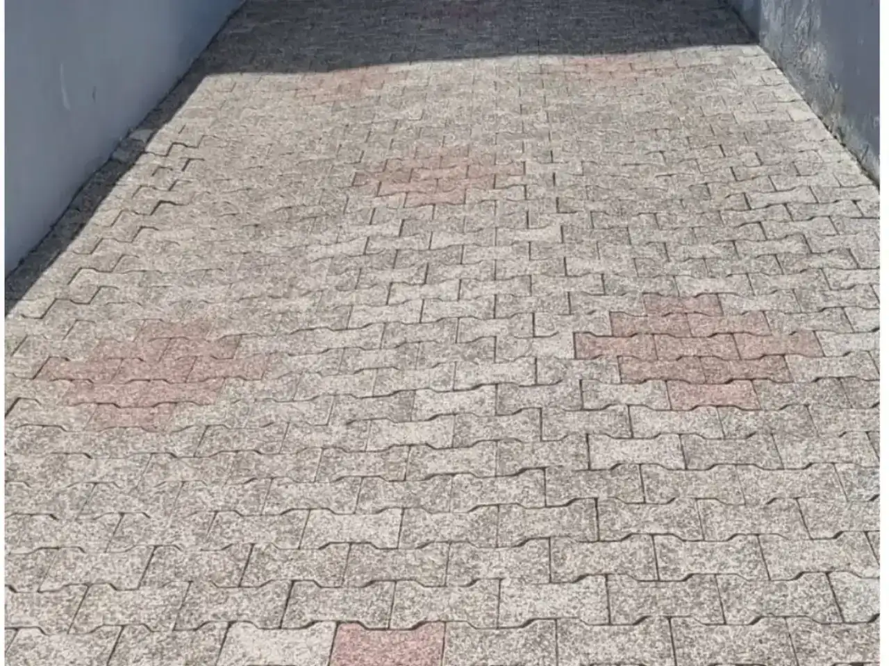 Schmale gereinigte Zufahrt aus Betonpflaster zwischen zwei Hauswänden